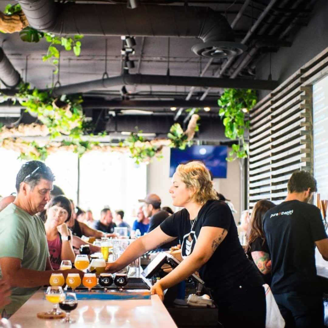 Bartender serving a flight of beers at Pure Project Brewing’s Balboa Park taproom in San Diego, California.