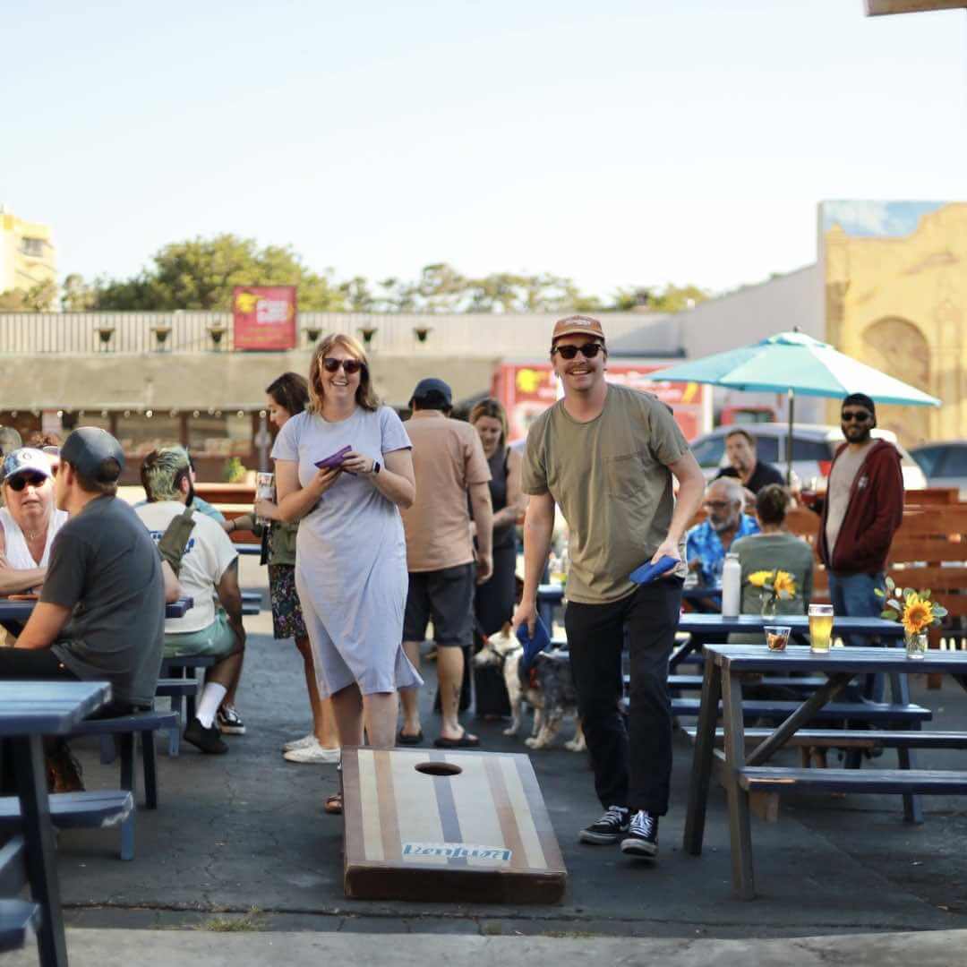 People playing cornhole and enjoying drinks at Ventura Coast Brewing Company’s outdoor patio in Ventura, California.