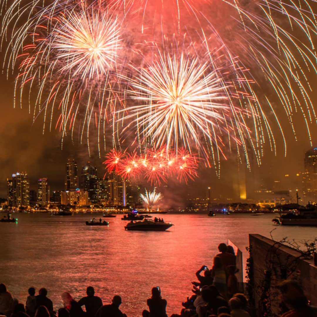 Fireworks over San Diego Bay during Big Bay Boom 4th of July celebration, with skyline and boats in view.