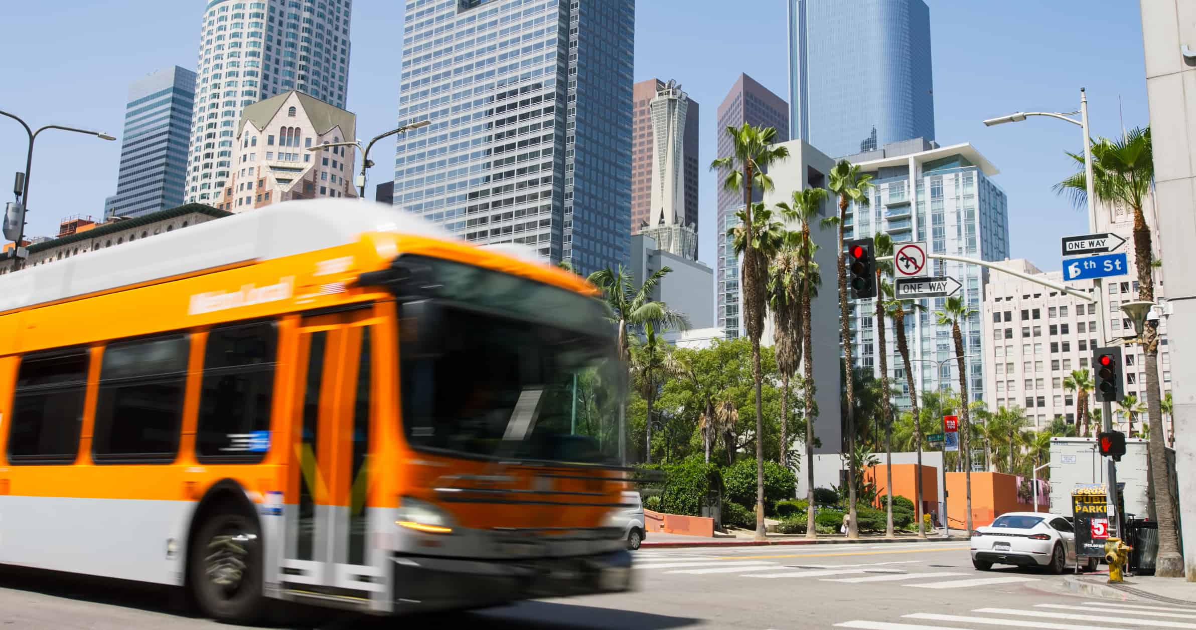 An orange LA Metro bus crosses an intersection in Downtown Los Angeles.