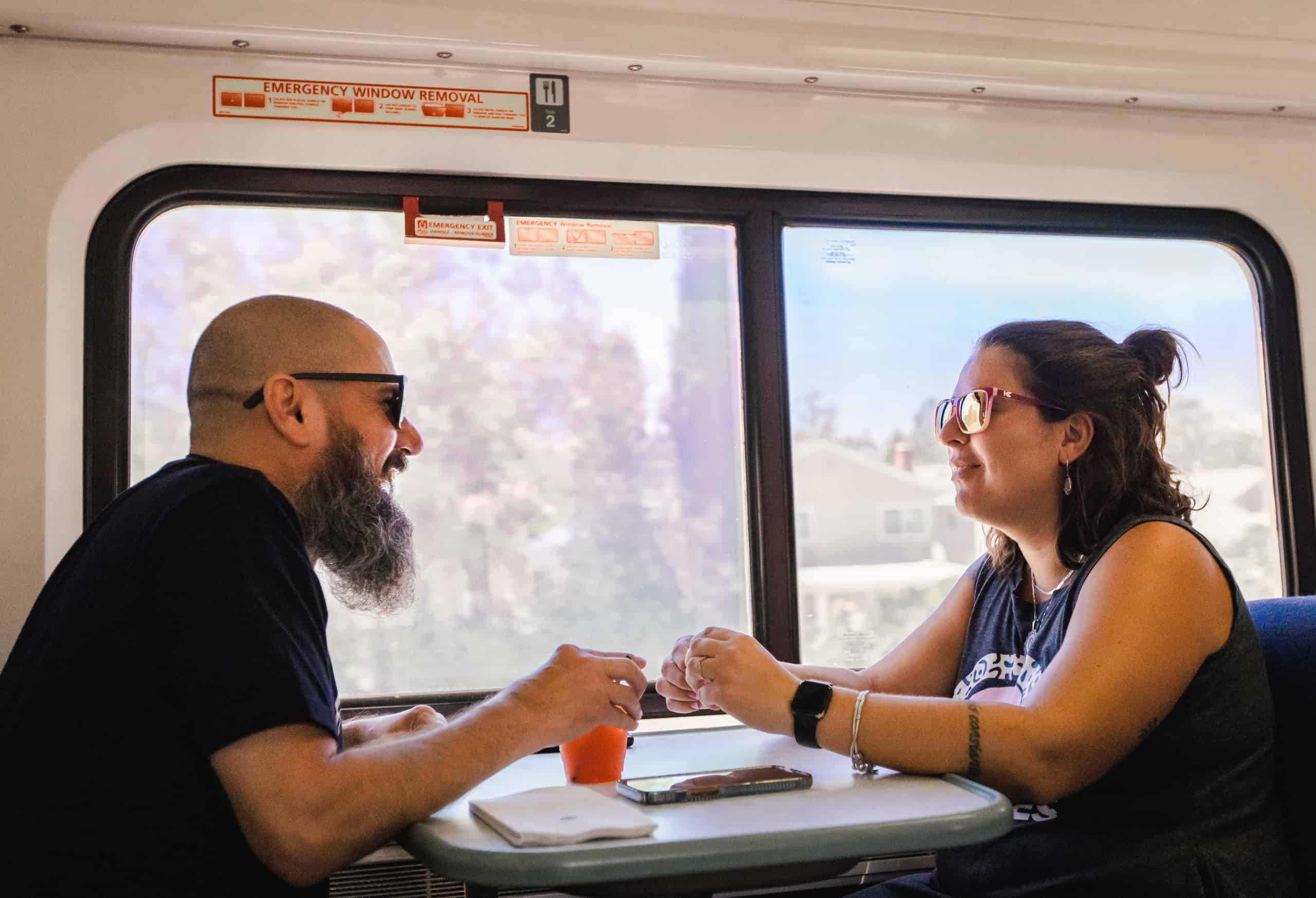Two sports fans relax at a table aboard the Pacific Surfliner on their way to a sporting event.