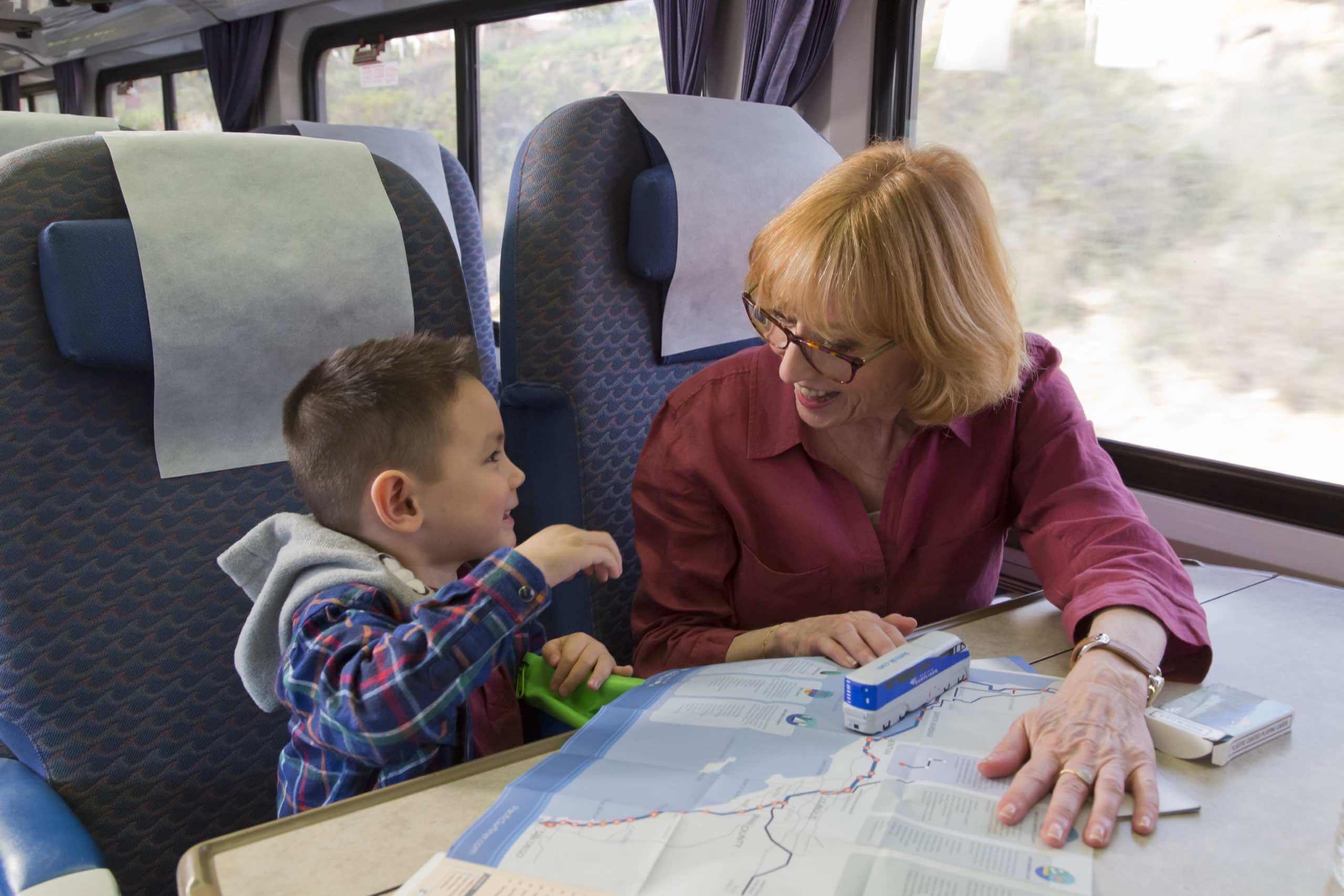 Family laughing and reviewing train route map while riding the Pacific Surfliner.