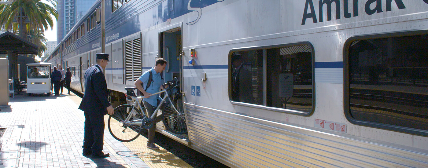 Passenger bringing a bicycle onboard the Pacific Surfliner for eco-friendly travel along the California coast.