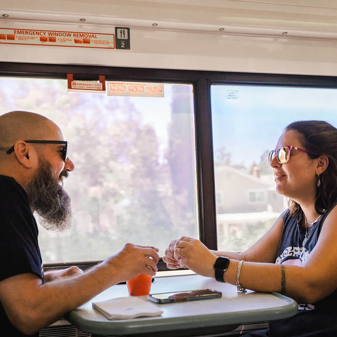 A couple enjoying drinks while traveling by train